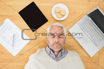 Mature man sleeping with electronics and biscuits on parquet floor