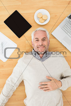 Man lying with electronics and biscuits on parquet floor