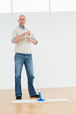 Full length portrait of a mature man standing with a mop