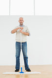 Full length portrait of a mature man standing with a mop