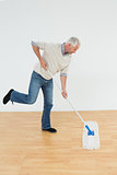 Full length side view of a mature man mopping the floor