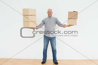 Smiling mature man carrying boxes in a new house