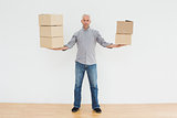 Serious mature man carrying boxes in a new house