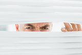 Close-up of a mature businessman peeking through blinds