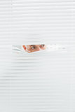 Close-up of a businessman peeking through blinds