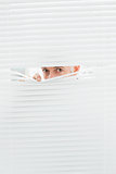 Close-up portrait of a businessman peeking through blinds