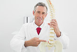 Smiling male doctor explaining spine in office