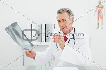 Confident doctor with x-ray picture of lungs in office