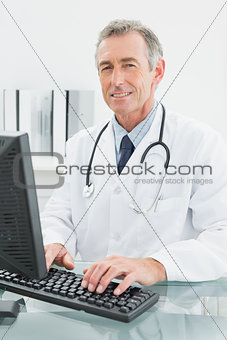 Smiling male doctor using computer at office