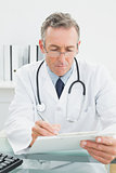 Doctor writing a report at desk in medical office