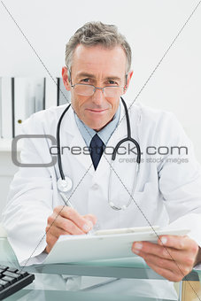 Portrait of a doctor writing a report at office
