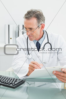 Male doctor writing a report at office