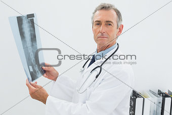 Serious doctor with x-ray picture of spine in office