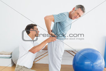 Therapist massaging mans lower back in gym hospital