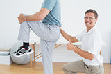 Therapist massaging mans lower back while gesturing thumbs up