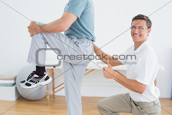Therapist massaging mans lower back while gesturing thumbs up