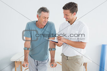 Therapist discussing reports with disabled patient in gym