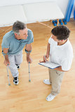 Therapist discussing reports with a disabled patient in gym hospital