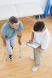 Therapist discussing reports with a disabled patient in gym hospital