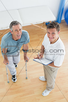 Male therapist discussing reports with a disabled patient in gym hospital