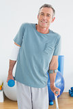 Smiling mature man with crutch and dumbbell