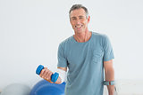 Mature man with crutch and dumbbells at gym hospital