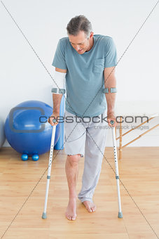 Mature man with crutches at gym hospital
