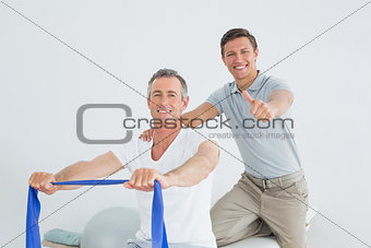 Therapist massaging a mans shoulder while gesturing thumbs up