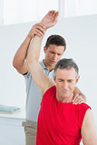 Physiotherapist stretching a mature mans arm
