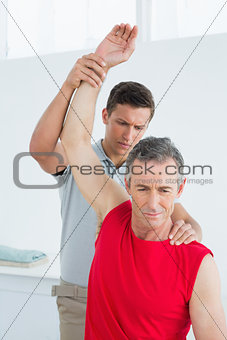 Physiotherapist stretching a mature mans arm