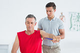 Male physiotherapist examining a mature mans arm