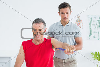 Physiotherapist examining a smiling mature mans arm