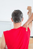 Rear view of a physiotherapist massaging mature mans arm