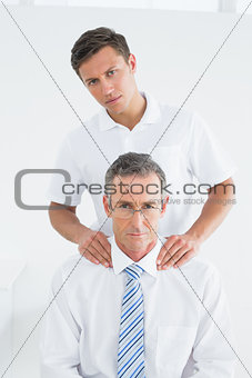 Male chiropractor and well dressed mature patient