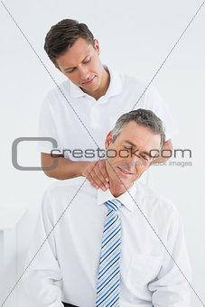 Male chiropractor massaging patients neck