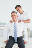 Chiropractor massaging a mature patients shoulder
