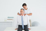 Chiropractor massaging a mature patients shoulder