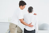 Rear view of a chiropractor examining man
