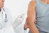 Cid section of a male doctor injecting a patients arm