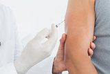 Mid section of a male doctor injecting a patients arm