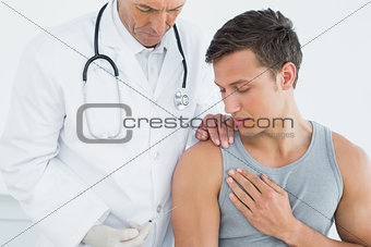 Male doctor injecting a patients arm