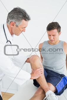 Displeased young man getting his leg examined