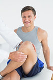 Portrait of a smiling young man getting his leg examined