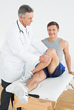 Portrait of a smiling young man getting his leg examined