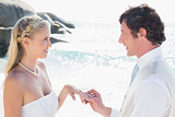 Man placing ring on pretty blonde brides finger