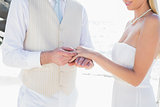Man placing ring on smiling brides finger