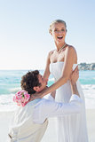 Laughing groom picking up his pretty blonde wife smiling at camera