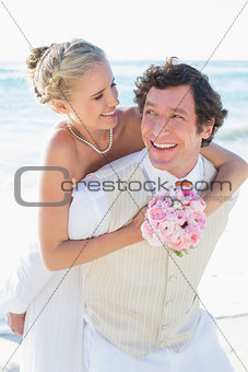Happy groom giving his blonde wife a piggy back
