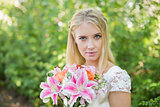 Blonde bride holding colourful bouquet looking at camera