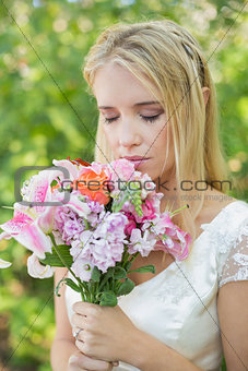 Blonde bride smelling her colourful bouquet